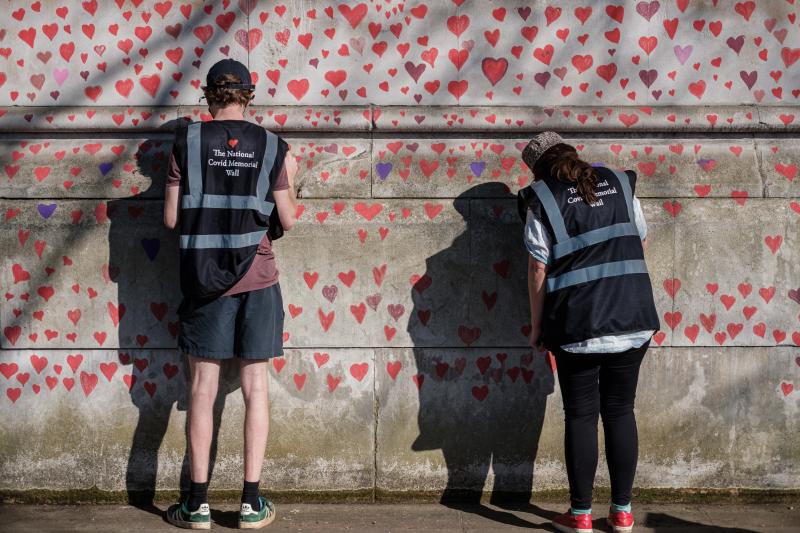 Two volunteers drawing hearts on the National Covid Memorial Wall in London