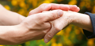 A white person holding another white person's hand with both hands in a caring way.
