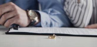 Wedding and engagement band resting on divorce paperwork