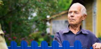 old man speaking to neighbour with blue fence between them 