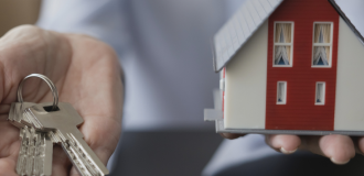 Keys and a small house in a woman's hands