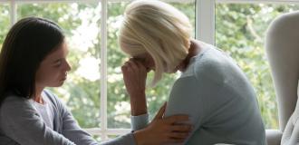 A bereaved woman is consoled by her daughter