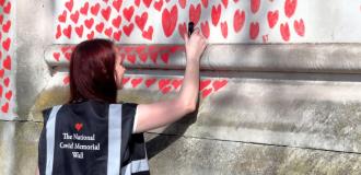 girl writing on covid 19 memorial wall