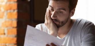Man reading a piece of paper seeming frustrated