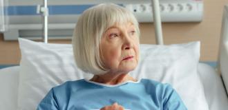 Elderly woman sat in hospital bed looking away from the camera 