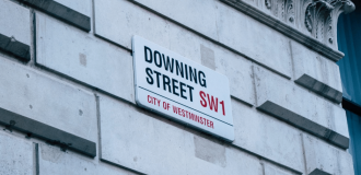 The Downing Street street sign on a white brick wall.