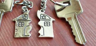 two sets of keys each with one half of a house keyring, separated with a jagged edge on a brown table