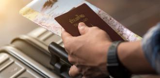 A hand holding a passport and other documents.