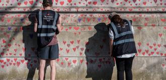 Two people looking at the covid memorial wall