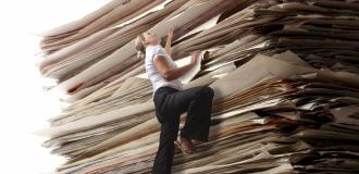 A woman climbing an enormous stack of papers.