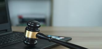 A Judge's gavel resting on the keyboard of a grey laptop.