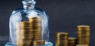 A pile of coins, some of which are under a glass bell jar 