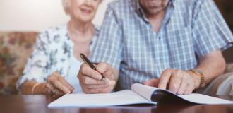 An elderly couple signing a piece of paper together