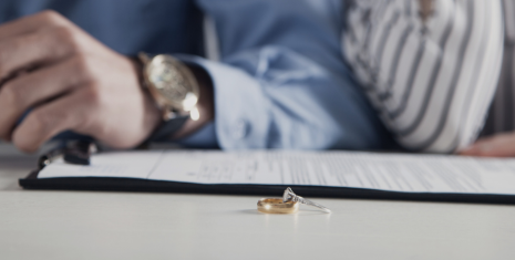 Wedding and engagement band resting on divorce paperwork