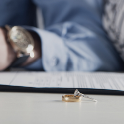 Wedding and engagement band resting on divorce paperwork