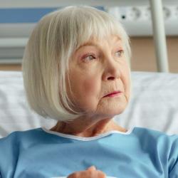 Elderly woman sat in hospital bed looking away from the camera 